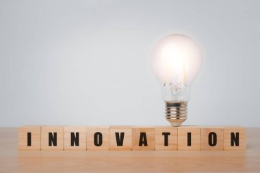 Tahta bloklar küp ile kelime yeniliği ve ahşap masa üzerinde ampul, yenilikçi teknoloji ağ bağlantısı ile yeni iş fikirleri.