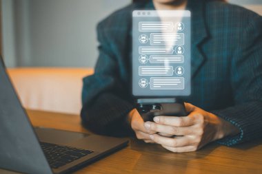 Modern ofis ortamında bilgisayarlı dijital iletişim için akıllı telefon kullanan bir iş adamı..