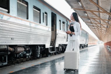 Tren istasyonunda bavullu bir kadın, yolculuk için hazır. Modern ulaşım ve seyahat kavramı.