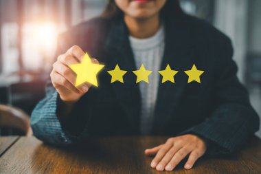 İş hayatında müşteri memnuniyeti ve kalite geribildirimi temsil eden bir yıldızı elinde tutan bir kadının yakın çekimi.