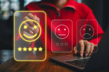 Bilgisayarda gülen yüzlü ve yıldız reytingli dijital geri bildirim sistemi kullanan birey, kullanıcı deneyimini vurguladı.