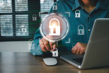 Modern ofis ortamında siber güvenlik ve veri korumasını sembolize eden, dijital kilit simgesine sahip bir dizüstü bilgisayar kullanan kişi.