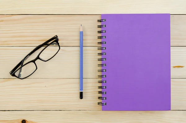 Fialové zápisník s tužkou a brýle — Stock fotografie