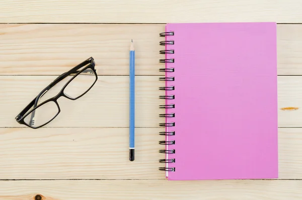 Růžový zápisník s tužkou a brýle — Stock fotografie