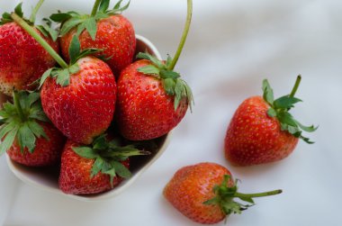 Beyaz kumaş arka plan üzerinde kase taze çilek.