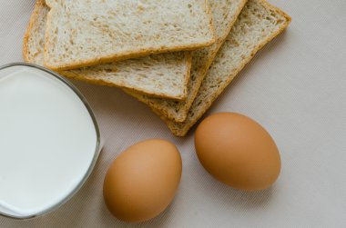 Kepekli ekmek, haşlanmış yumurta ve süt kahvaltı için dilimlenmiş.