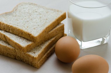 Kepekli ekmek, haşlanmış yumurta ve süt kahvaltı için dilimlenmiş.