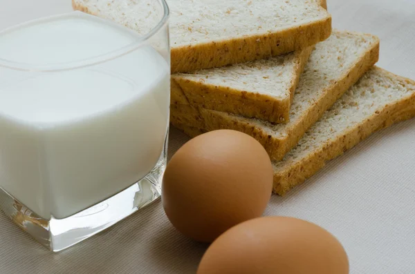 Pieczywo pełnoziarniste, gotowane jajko i mleko na śniadanie w plasterkach. — Zdjęcie stockowe