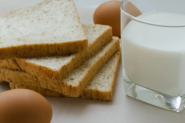 Geschnittenes Vollkornbrot, gekochtes Ei und Milch zum Frühstück. — Stockfoto