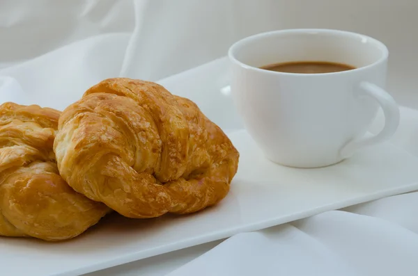 Croissant a kafe k snídani. — Stock fotografie