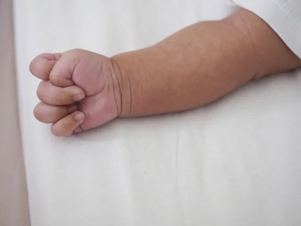 Yeni doğmuş bebek eli beyaz yatakta