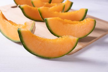 Beyaz ahşap arka planda dilimlenmiş olgun tatlı kavun dilimleri