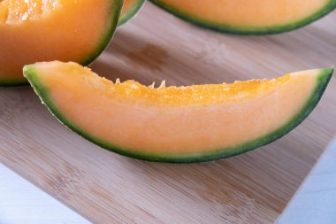 Dilimlenmiş tatlı kavun, ahşap bir tahtanın üzerinde, yakın plan.