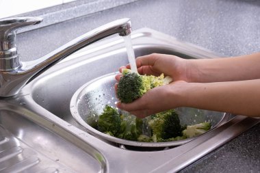 Brokolinin ellerinde. Mutfakta akan suyun altında.