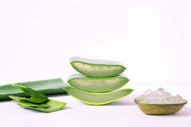 Kesilmiş üç sulu parça aloe vera beyaz arka planda üst üste uzanıyorlar.