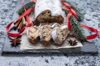 Dilimlenmiş noel pastası badem ezmesi, fındık ve parşömen kağıdının üzerinde dokuma arka planına karşı kuru üzüm.