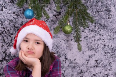 Küçük bir kız karlı bir arka planda tatilde sıkıldı.