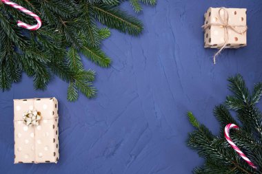 hediyeler ve ladin dalları mavi bir arka planda masanın üzerinde uzanır.