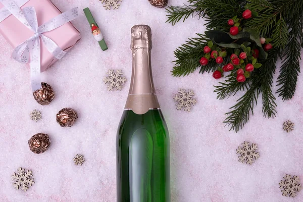 Şampanya şişesi beyaz bir arka planda karla kaplı bir masada yatıyor.