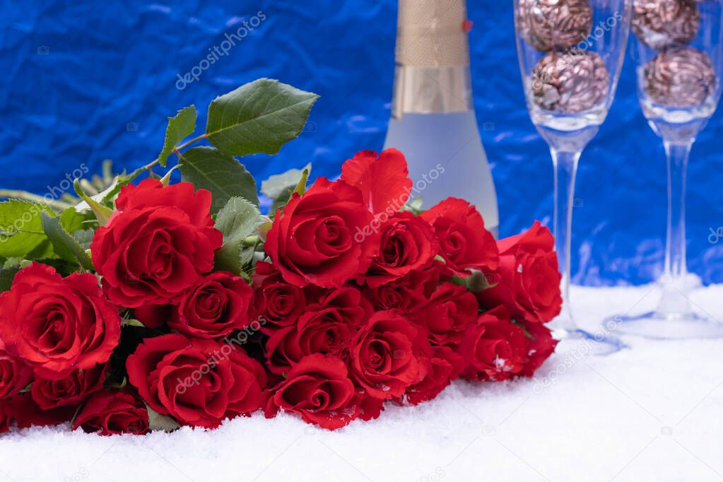 snow, a bouquet of red roses on a blue background, next to champagne, festive table