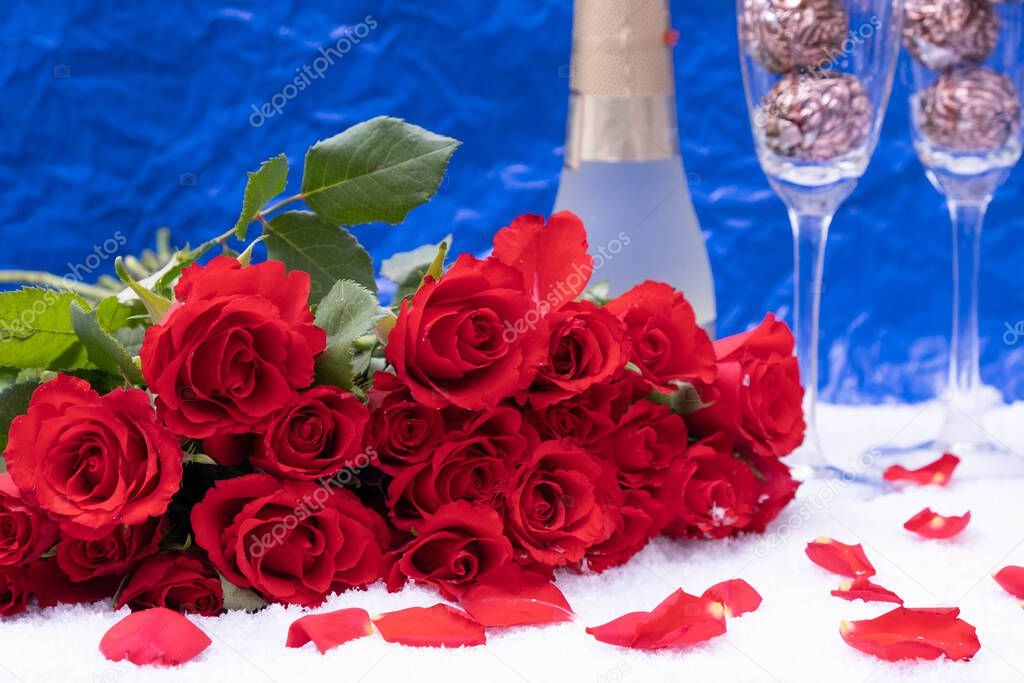 rose petals, snow, a bouquet of red roses on a blue background, next to champagne, festive table