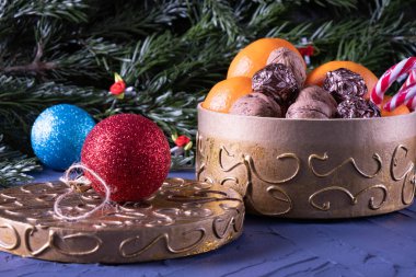 Noel süslemeleri, fındıklar, Noel köknar dalları, mavi arka planda bir kutuda şekerler