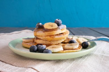 Bal ve böğürtlen akan taze gözlemeler ve masada doğranmış muzlar.