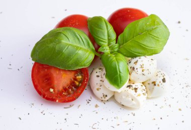 Domatesli mozzarella ve üzerine baharat serpiştirilmiş fesleğen ve bir tuğla arka planda beyaz bir masanın üzerine sos serpiştirilmiş.
