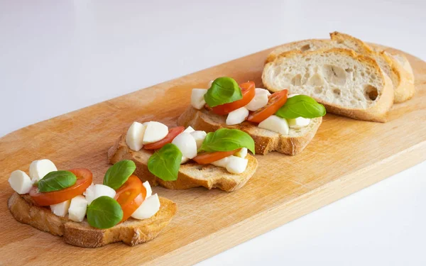 Drewnianej Desce Leżą Krakersy Mozzarellą Świeżą Bazylią Pomidorami Białym Tle — Zdjęcie stockowe
