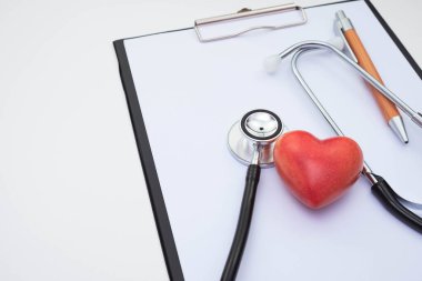 stetoskop ve kırmızı taş yapay kalp ve masa üzerindeki beyaz arka plan üzerine not kağıdı