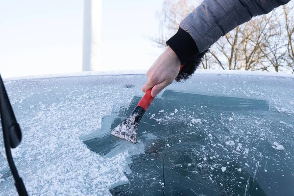 一个人在街上把汽车的挡风玻璃从冰上擦了一半 — 图库照片