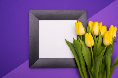 Siyah çerçeve ve bir buket sarı lale, sağ tarafta, leylak arka planda.