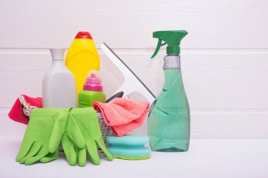 Beyaz arka planda yeşil eldivenler, paçavralar, deterjanlar ve fırçalar.