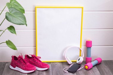 Evde egzersiz - dambıl ve spor ayakkabısı, plaka, sarı çerçeveli, notlar, kulaklıklar ve cep telefonu için, beyaz arka planda yeşil büyük yapraklar