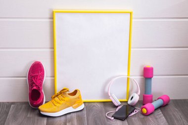 Dambıllar ve renkli spor ayakkabılar, plaka, sarı çerçeveli, notlar, kulaklıklar ve beyaz arka planda bir cep telefonu için.