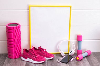 Spor salonları - dambıllar ve pembe spor ayakkabılar, masaj rulosu, plaka, sarı çerçeveli, notlar, kulaklıklar ve beyaz arka planda bir cep telefonu için