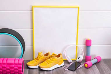 Sarı spor ayakkabılar, masaj ruloları ve halterler, plaka, sarı çerçeveli, notlar, kulaklıklar ve beyaz arka planda bal peteği için