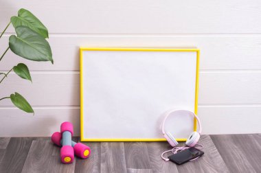 Beyaz arka planda notlar, dambıllar, kulaklıklar, cep telefonları ve büyük yeşil yapraklar için plaka