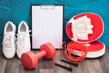 kırmızı - dambıllar, ip atlama ve tekme pedleri, not panosu ve beyaz spor ayakkabılar, yakın plan ve mavi arka plan