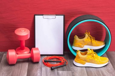 kırmızı halterler, atlama halatı ve sarı spor ayakkabılar, not panosu ve masaj silindiri - evde spor