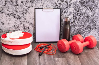 Evdeki spor aletleri - kırmızı halterler, atlama halatı ve panç pedleri, su şişesi ve not panosu, desenli arka plan