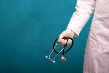 Doktor ve elinde steteskop var, dokulu, mavi arka planda.