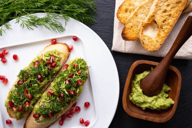Sağlıklı atıştırmalıklar hazırla - avokado, olgun nar tohumları serpiştirilmiş, susam tohumu ve taze dereotu, yakın çekim