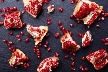 Siyah zemin üzerinde olgun nar dilimleri, yakın plan.