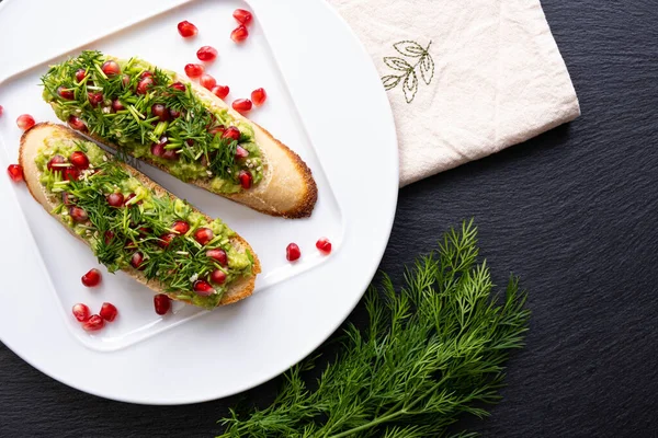 Hay Dos Bocadillos Plato Blanco Aguacate Espolvoreado Con Semillas Granada —  Fotos de Stock