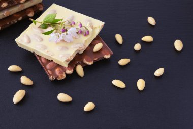 Siyah bir zemin üzerine badem ve badem serpiştirilmiş süt ve beyaz çikolata.