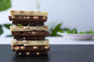 Siyah arka planda fındıklı siyah, beyaz ve sütlü çikolata kalıpları var.