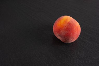 Olgun şeftali siyah bir arkaplanda yatıyor, yakın plan.