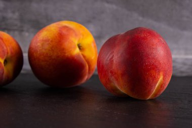 Şeftaliler siyah bir arkaplanda uzanır, yakın plan.