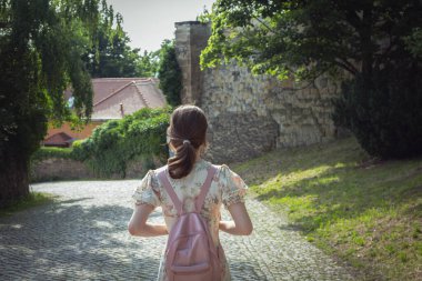 Pembe sırt çantalı bir kız şehirde, Avrupa 'da, Almanya' da dolaşıyor.